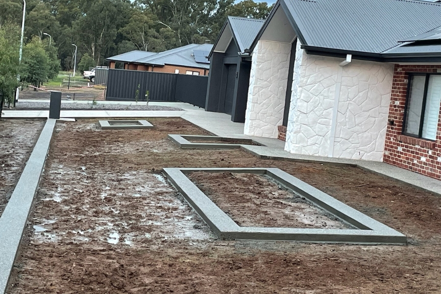 Concrete mower strips and garden bed frames set into the front yard before turf, Maiden Gully.