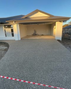 Finished exposed aggregate driveway that reflects typical concrete driveway cost, weatherboard home, Axedale.