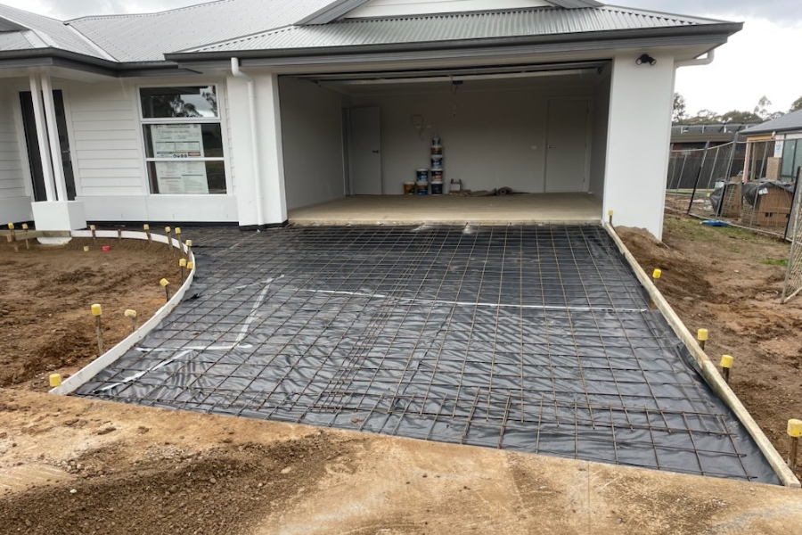 Concrete driveway preparation underway with steel mesh and moisture barrier laid before the pour, Axedale.