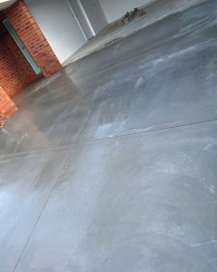 Freshly poured concrete driveway with a glossy wet finish beside a red brick feature wall, California Gully.