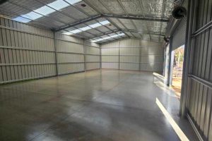 Cured infill shed slab inside a large portal-frame kit shed with foil-backed insulation ceiling, Bendigo region.