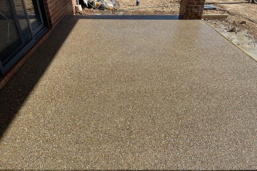Warm-toned exposed aggregate colours, alfresco corner beside a sliding door, red-brick home, Strathdale.