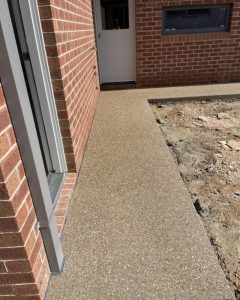 Warm honey and gold exposed aggregate colours on a path against a red-brick Strathdale home.