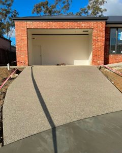 Finished exposed aggregate concrete driveway leading to a red brick garage, Flora Hill.