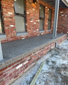 Close-up of an exposed aggregate ledge cap on a heritage brick home near the entry light, Kennington.