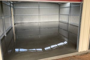 Freshly poured infill shed slab with wet reflective finish inside a small kit shed, around Bendigo.