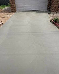 Freshly trowelled plain concrete driveway with a fan-pattern finish beside a brick garage, North Bendigo.