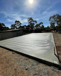 Shed slab cost in Bendigo — freshly poured kit-shed slab with rebated edge and tie-down stirrups, Bendigo.