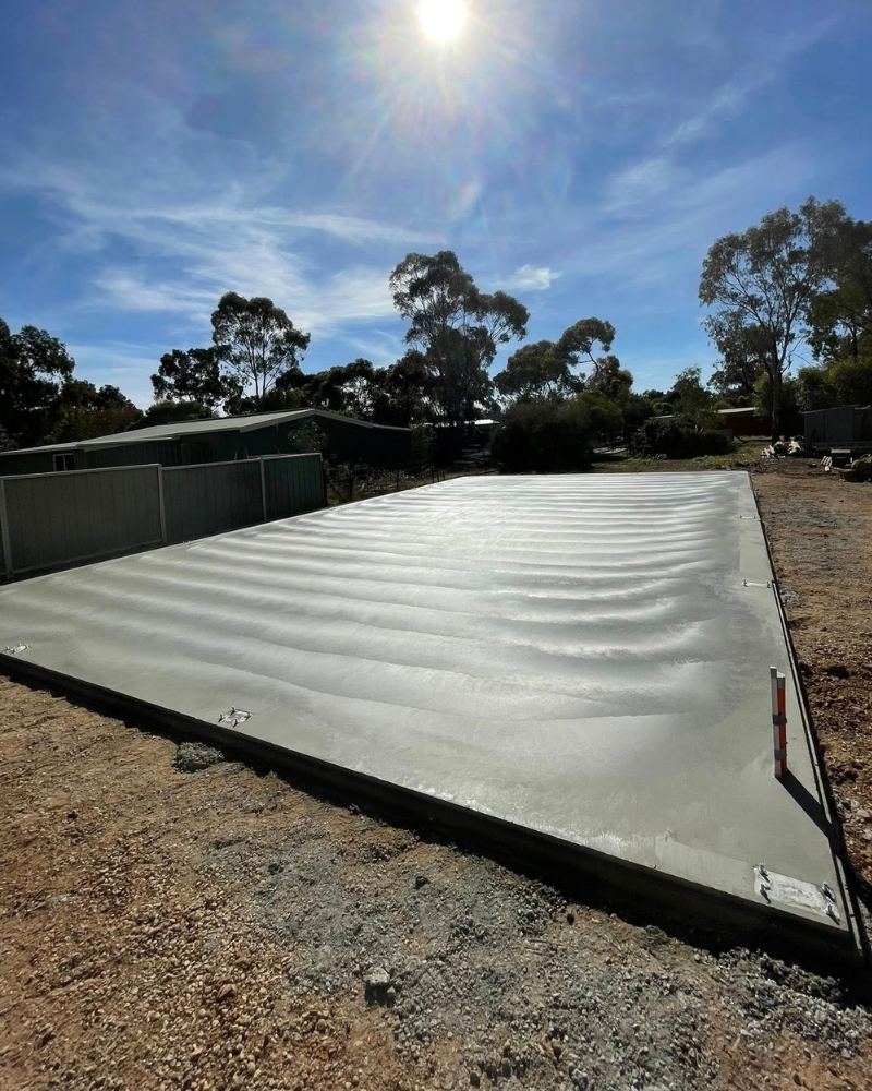 Shed slab cost in Bendigo — freshly poured kit-shed slab with rebated edge and tie-down stirrups, Bendigo.
