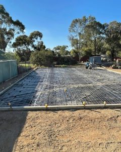 Shed slab prep with formwork, moisture barrier, mesh on chairs and tie-down stirrups, Central Victoria.