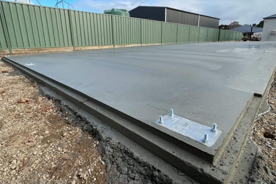 Rebated edge and tie-down bracket close-up — how a shed slab keeps vermin out and holds the build down, around Bendigo.