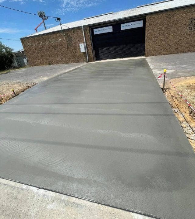 Plain concrete driveway freshly poured leading to a shed with a roller door, Bendigo.